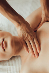 Hands of female chiropractor massaging shoulders of young woman lying on massage table. Concept of physical therapy treatment ,neck pressure point