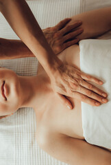 Hands of female chiropractor massaging shoulders of young woman lying on massage table. Concept of physical therapy treatment ,neck pressure point