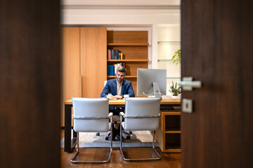 Modern luxurious office interior and handsome company director working on financial reports.