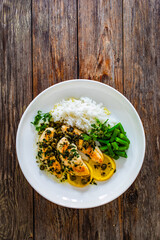 Chicken piccata with white rice and capers in sauce on wooden background
