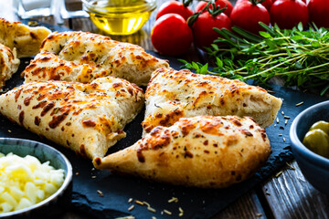 Focaccia alle olive - baked sandwich with green olives and rosemary on wooden background
