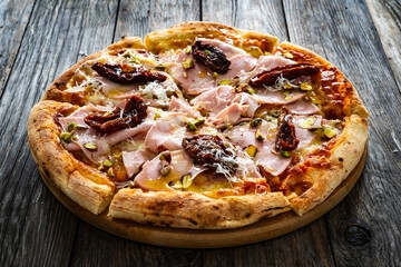 Pizza mortadella with mozzarella cheese and sun dried tomatoes on wooden table
