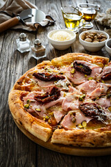 Pizza mortadella with mozzarella cheese and sun dried tomatoes on wooden table
