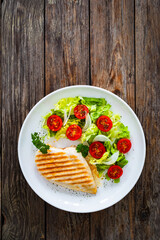 Grilled chicken breast and fresh vegetables on wooden table