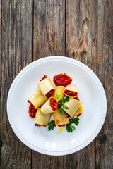 Paccheri con ragù alla bolognese - noodles with bolognese  sauce on wooden table