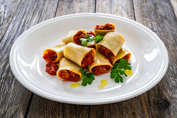 Paccheri con ragù alla bolognese - noodles with bolognese  sauce on wooden table