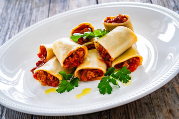 Paccheri con ragù alla bolognese - noodles with bolognese  sauce on wooden table