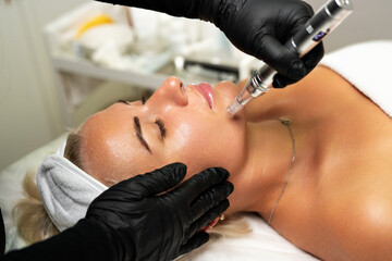 Microneedle RF lifting procedure. A cosmetologist performs a facial rejuvenation procedure on a...