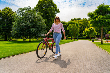 Beautiful mid adult woman riding bicycle in city park
