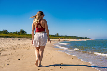 Beautiful mid adult woman walking on sunny beach
