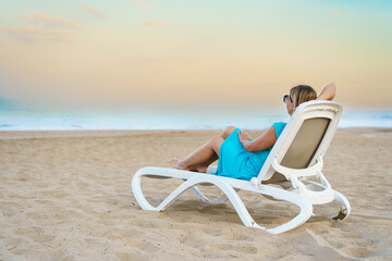 Woman relaxing on beach sitting on sunbed
