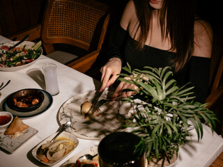 The woman eats seafood in a luxury restaurant. Dark mood.