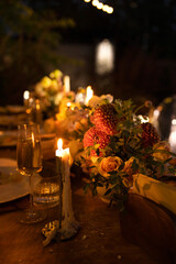 Wedding table for guests, decorated with candles, are served with cutlery and crockery and covered with yellow tablecloth