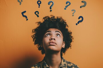 African American teen gazing upwards at floating question marks, orange backdrop - obrazy, fototapety, plakaty