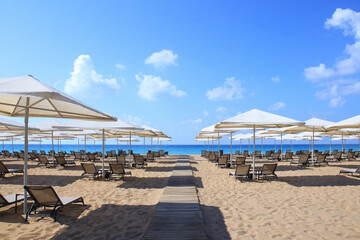 Beautiful tropical scenery. Sun beds, loungers, umbrella. Sea. Resort hotel. Rows of folded beach umbrellas and empty sunbeds on the beach. Leisure concepts. Vacation and summer concept. Travel 