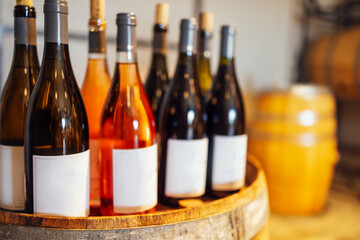 Obraz premium Close up of mockup of group of glass bottles with different wines and champagne on wooden wine barrel