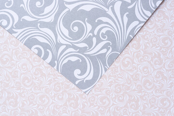 overlapping decorative scrapbooking paper with floral patterns or swirls in silver gray and beige