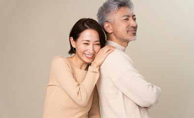 日本人ミドル世代夫婦のポートレート/男性の背中にもたれかかり微笑んでいる女性