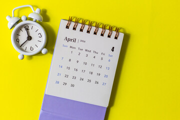 Desk calendar for April 2024 and clock on a yellow background.