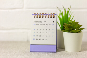 Desk calendar for February 2024 and on the table with copy space.