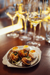 An exquisite delicacy of snails on a metal tray. Escargot with herbs on a platter on a wooden table.