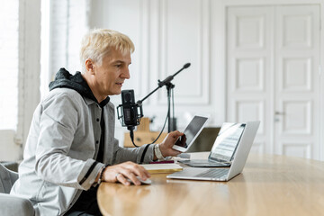Podcaster setting up his tablet and microphone in a stylish room, preparing for a recording session.