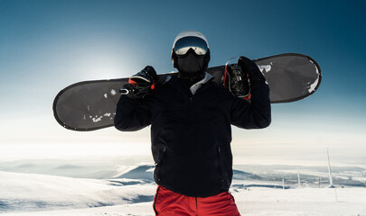 Snowboarder with gear enjoys the mountain's peak, ready for an adrenaline-filled descent.