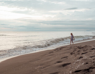 A girl walks along the sandy beach. Sea coast.
