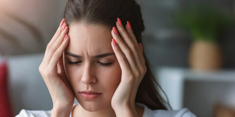 Naklejka premium A woman holding her head. Stressed, upset, or has a headache. Feeling overwhelmed. high workload. Migraine.