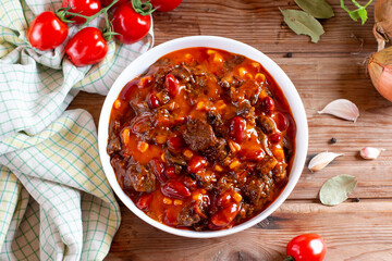 Hot and spicy fresh made mexican dish chili con carne soup with meat, vegetables and red beans on table. Goulash