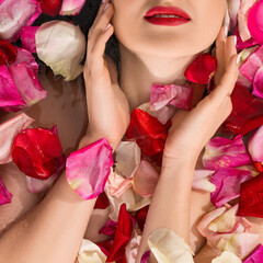 Sensual woman lying in water and rose petals