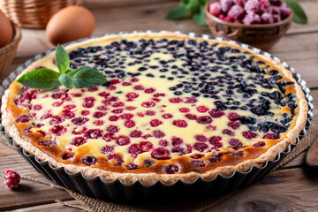 Blueberry and raspberry pie in a ceramic dish on a wooden table.