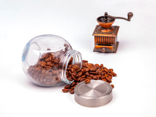 Seeds of coffee are scattered from glass transparent capacity on a table - 703930698