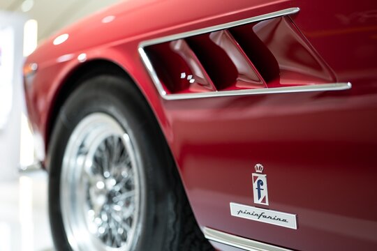 Detail of Ferrari 275 GTS red sports car in Museum Enzo Ferrari Modena focused on Pininfarina logo