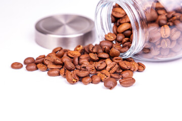 Seeds of coffee are scattered from glass transparent capacity on a table - 703931083