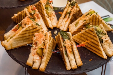 Sandwiches on a black plate. Snack at the banquet.