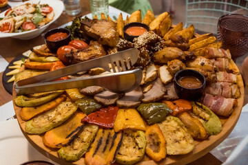 Sliced ​​meat and vegetables on a plate at a banquet. Baked vegetables on a platter.