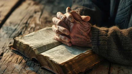 Foto auf Acrylglas Alte Türen Person's hands folded in prayer over an open, well-worn bible, resting on a wooden table