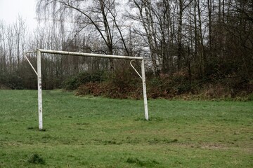 poorly maintained soccer pitch with old soccer goal in the rain