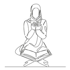 Muslim girl prays in front of the Koran