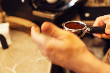 Barista grinding freshly roasted coffee beans from a professional modern electric grinder into a powder