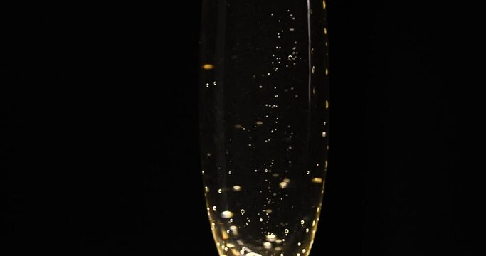 Glass of champagne on a black isolated background. Capturing the effervescence: Slow-motion, super macro shot showcasing delicate champagne bubbles gracefully rising in an elegant glass against a pris