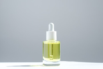 Skin care serum in a glass bottle with pipette on the background