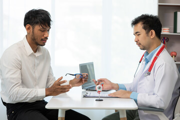 Close-up of an Asian male doctor showing an eyeball model and explaining eye diseases to a male...