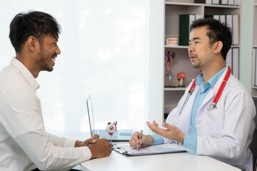 Close-up of an Asian male doctor showing an eyeball model and explaining eye diseases to a male...