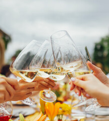 Female hands holding elegant glasses with long stem of champagne and and clink them on the...