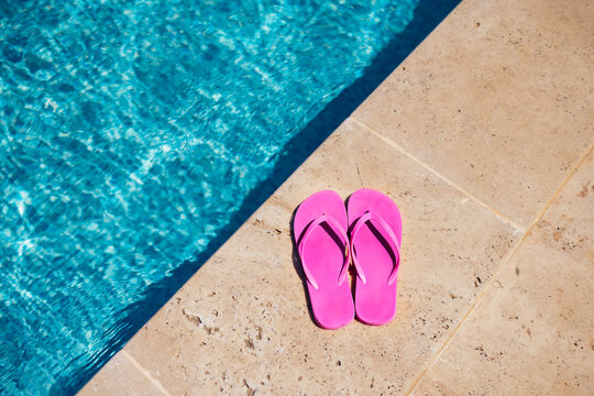 Pink flipflop on the granite poolside while vacation at the hotel.