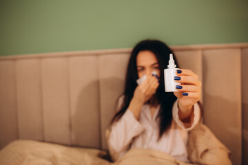 Woman is having allergies and she is using nasal spray to help herself. Woman using nasal spray....
