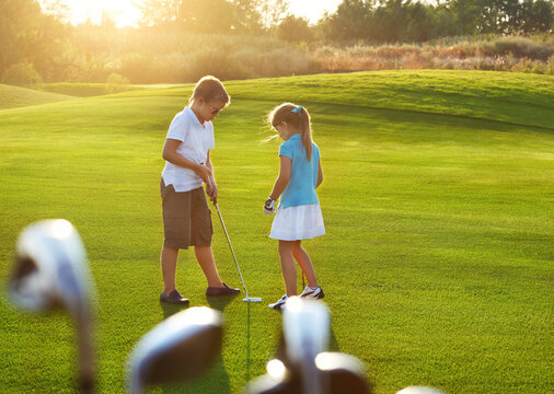 Casual kids at a golf field holding golf clubs