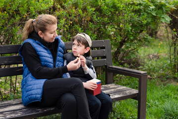 A mother and her son talk in the park and eat popcorn, the boy is sad, the mother tries to explain...